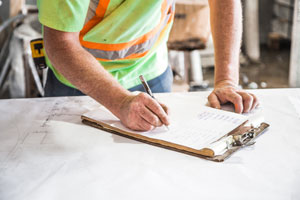 Person Writing On Blueprints or Drawing In Construction Business Photo